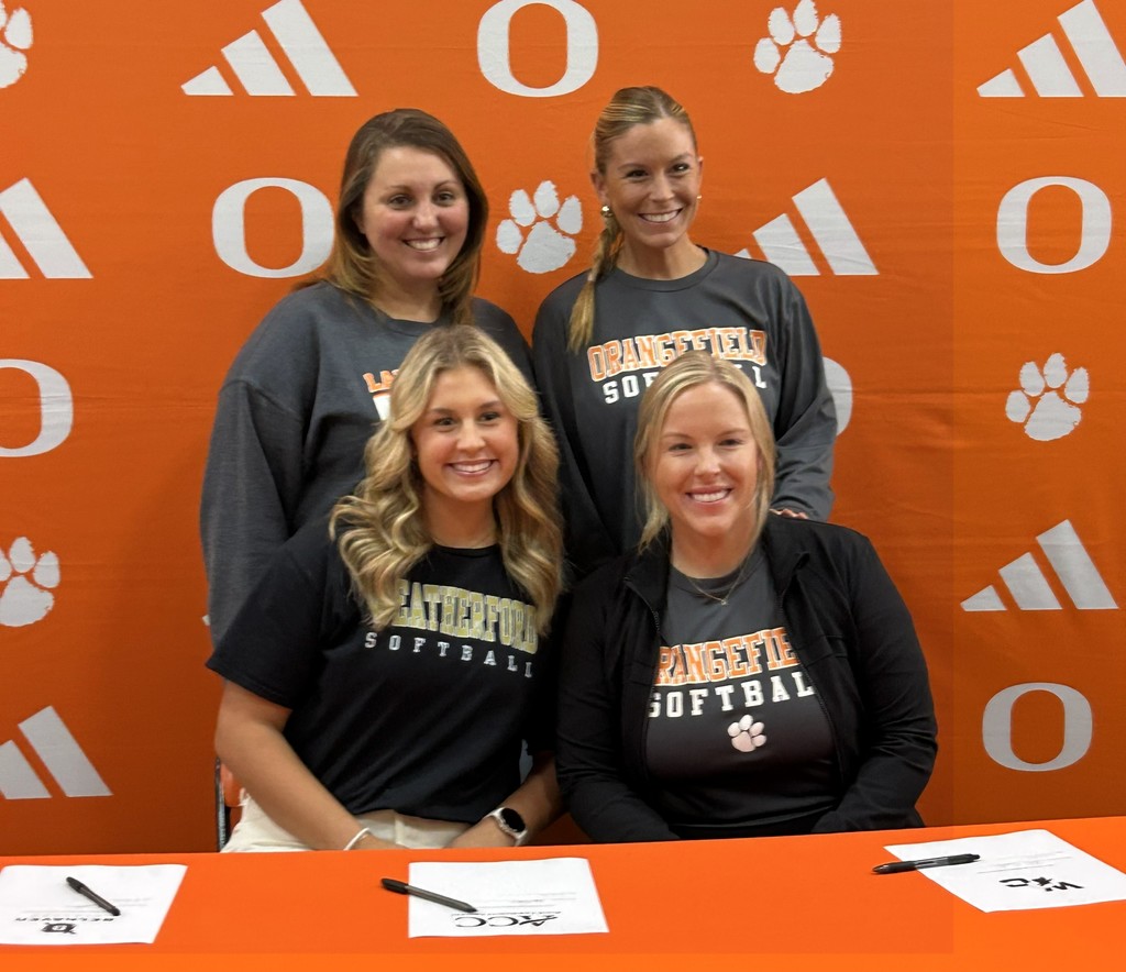 two coaches standing and one sitting with a student in a black shirt