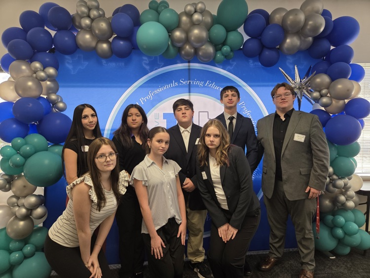 students dressed to compete in front of a baloon arch