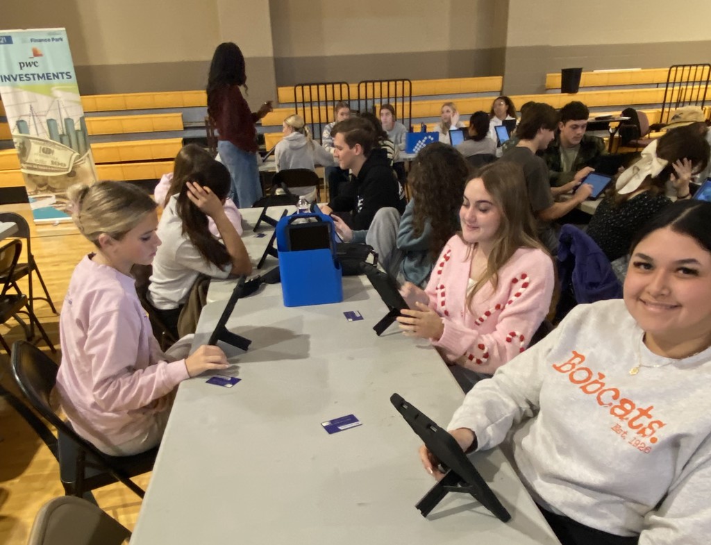 students using a tablet at tables in a gym