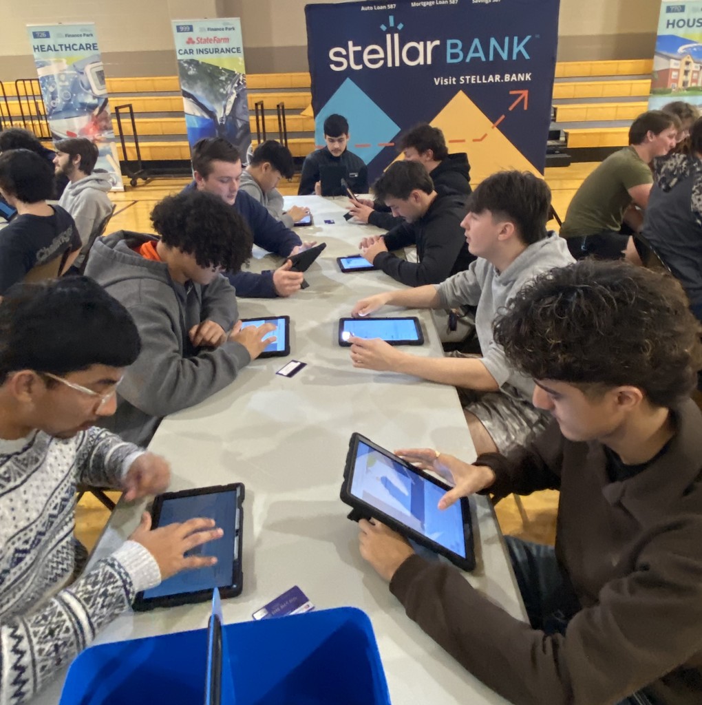students using a tablet at tables in a gym