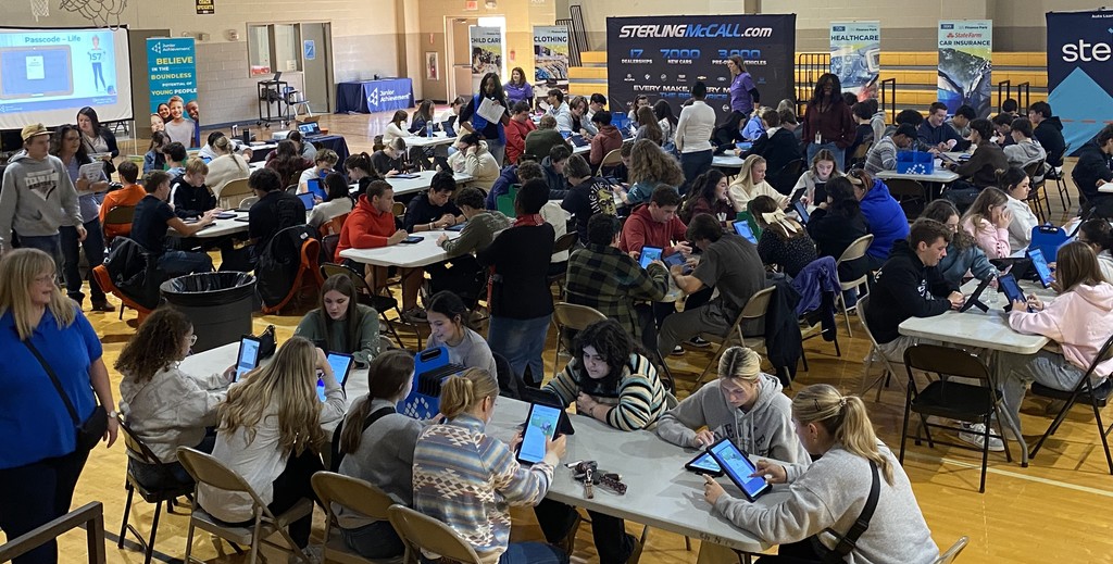 students sitting at tables using a tablet
