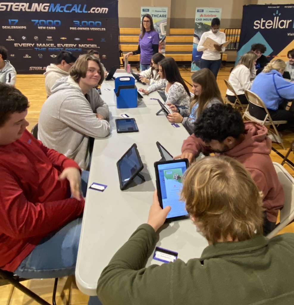 students using a tablet at tables in a gym