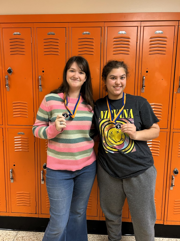 two students in front of orange lockers with medals