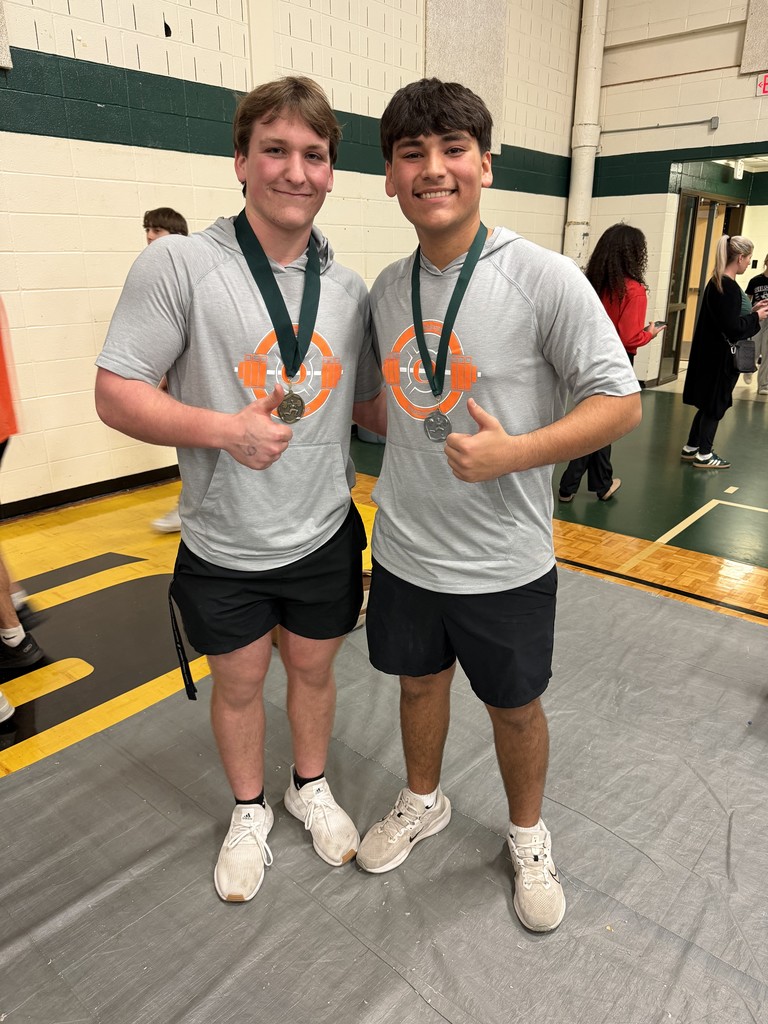 Two individuals wear matching gray t-shirts and black shorts. They each have medals around their necks.