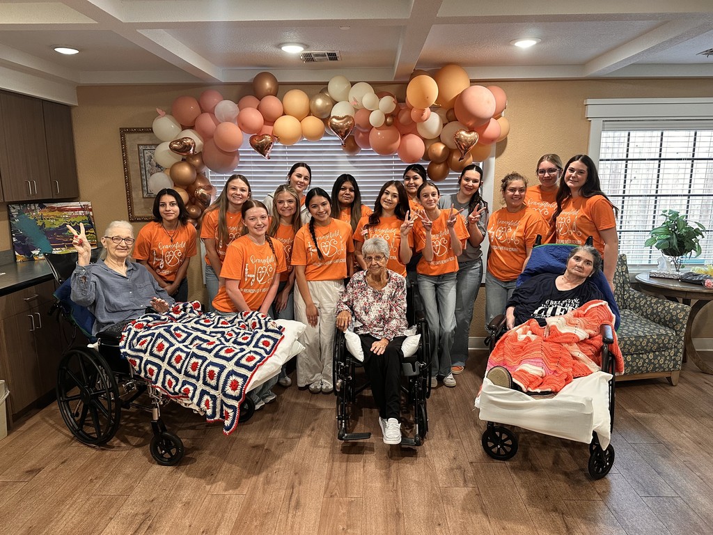 students in orange shirts with nursing home residents