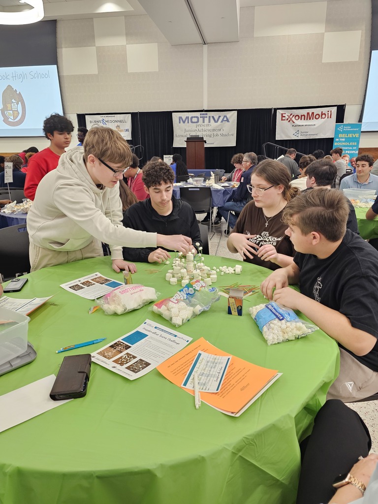 Group of students sit around a table, engaged in an activity with various materials.