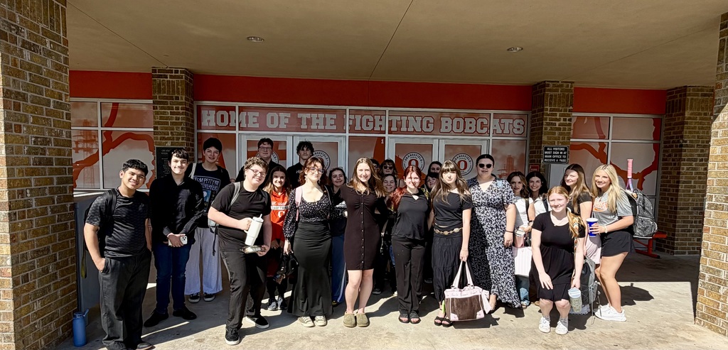 A group of students poses for a photo in front of a building with "Home of the Fighting Bobcats" on it.