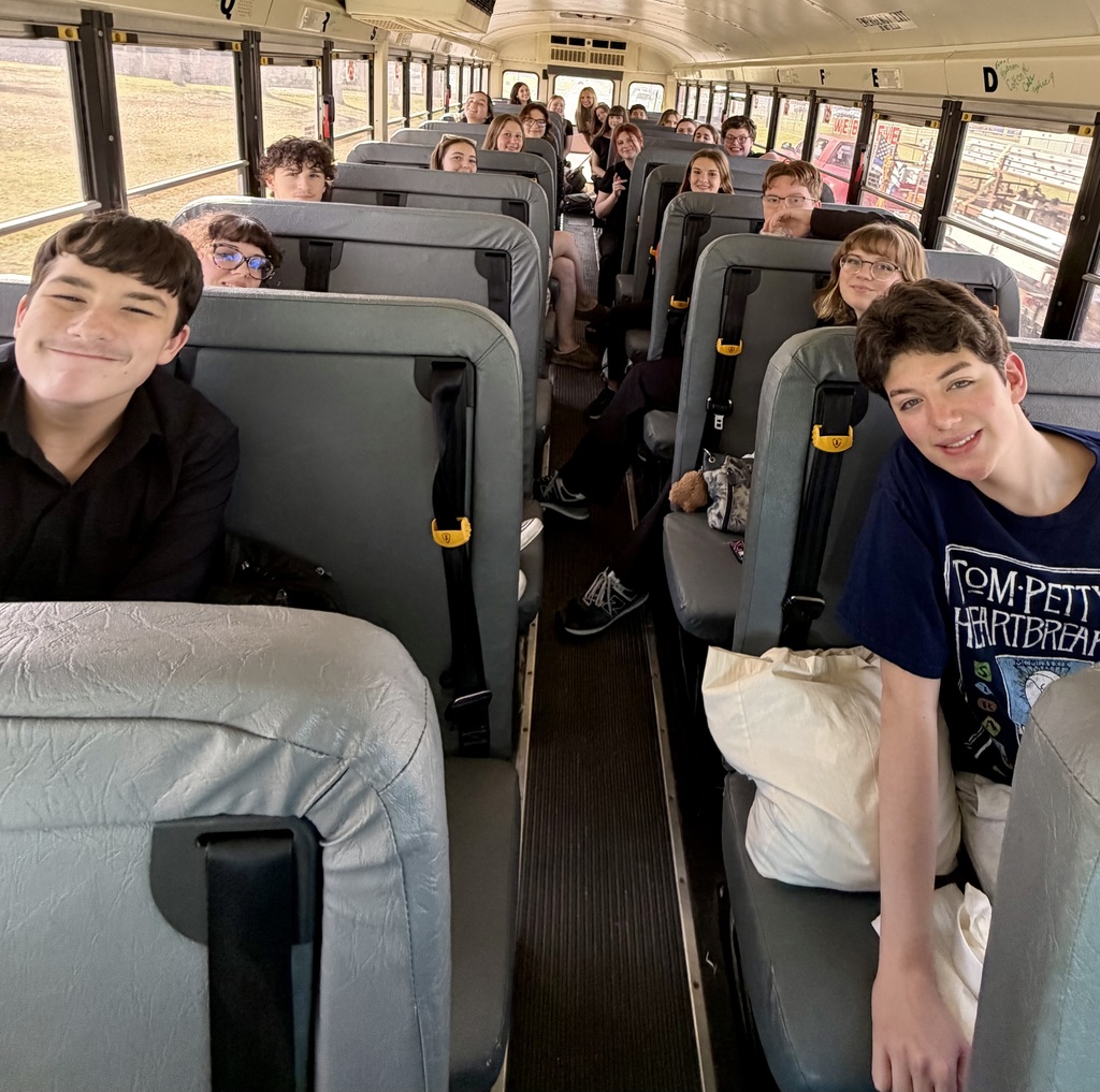 A school bus filled with students; two smiling boys sit in the front seats.