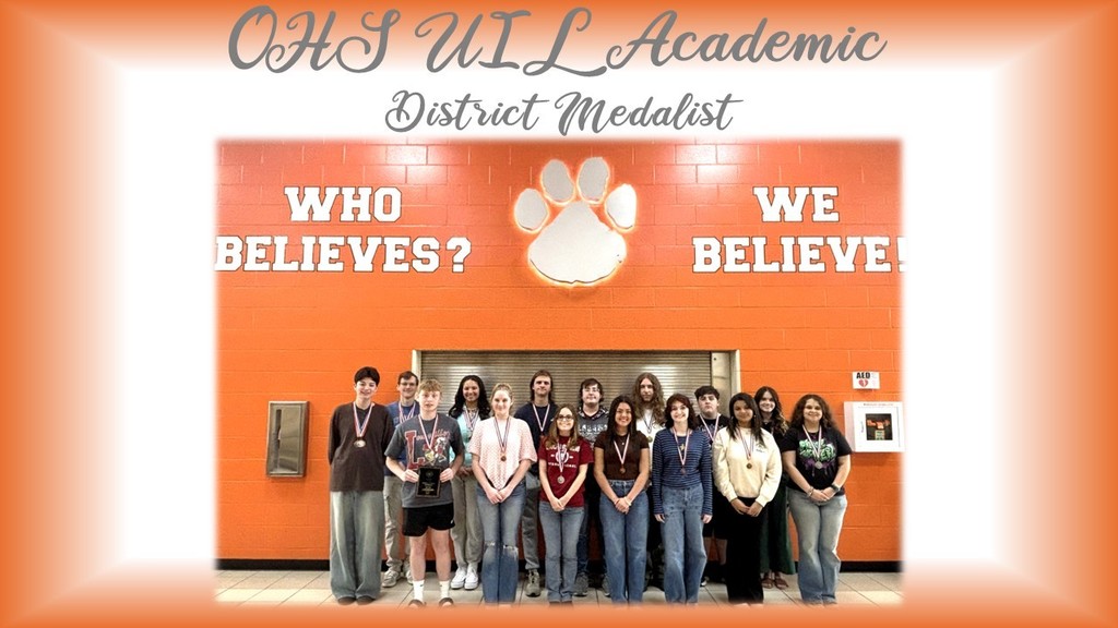 A group of people stand in front of an orange wall with "Who Believes? We Believe" and a paw print.