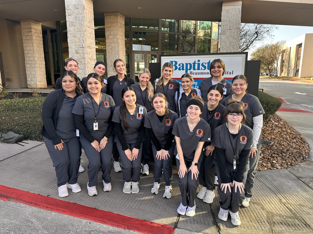 Group of medical students in uniform standing outside a building, smiling for a photo.