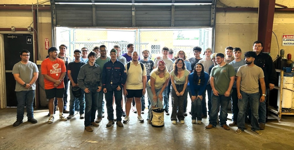 Group of people in a workshop, with some in shorts, others in jeans.