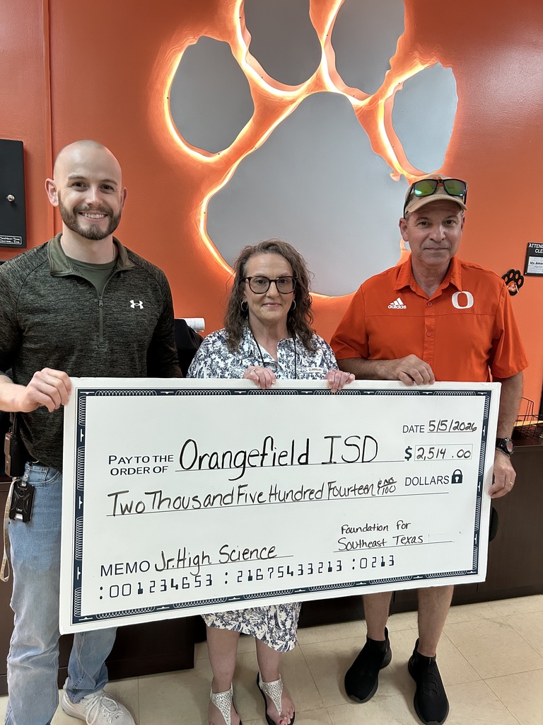 Three individuals standing behind a large check, with one holding it, in front of an orange wall with paw prints.