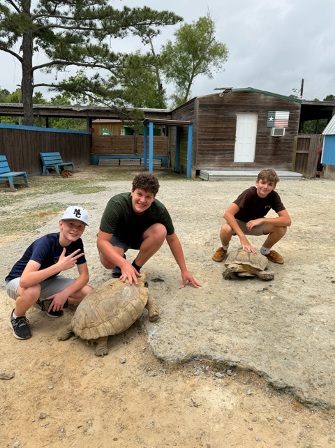 8th graders pose for a picture with tortoises.