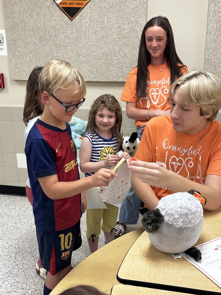 Children and teenagers work on a stuffed animal while one girl holds a stuffed toy.