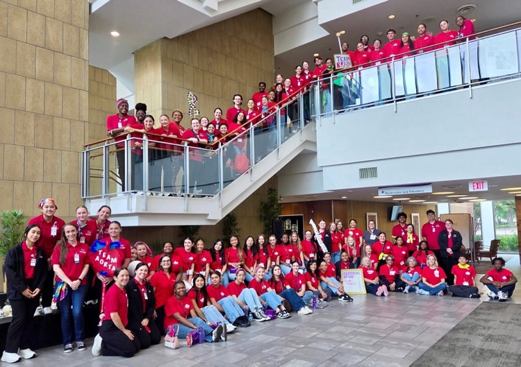 large group of students in red shirts, some on a large staircase