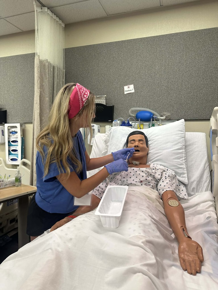 student in blue shirt checking on a mannequin