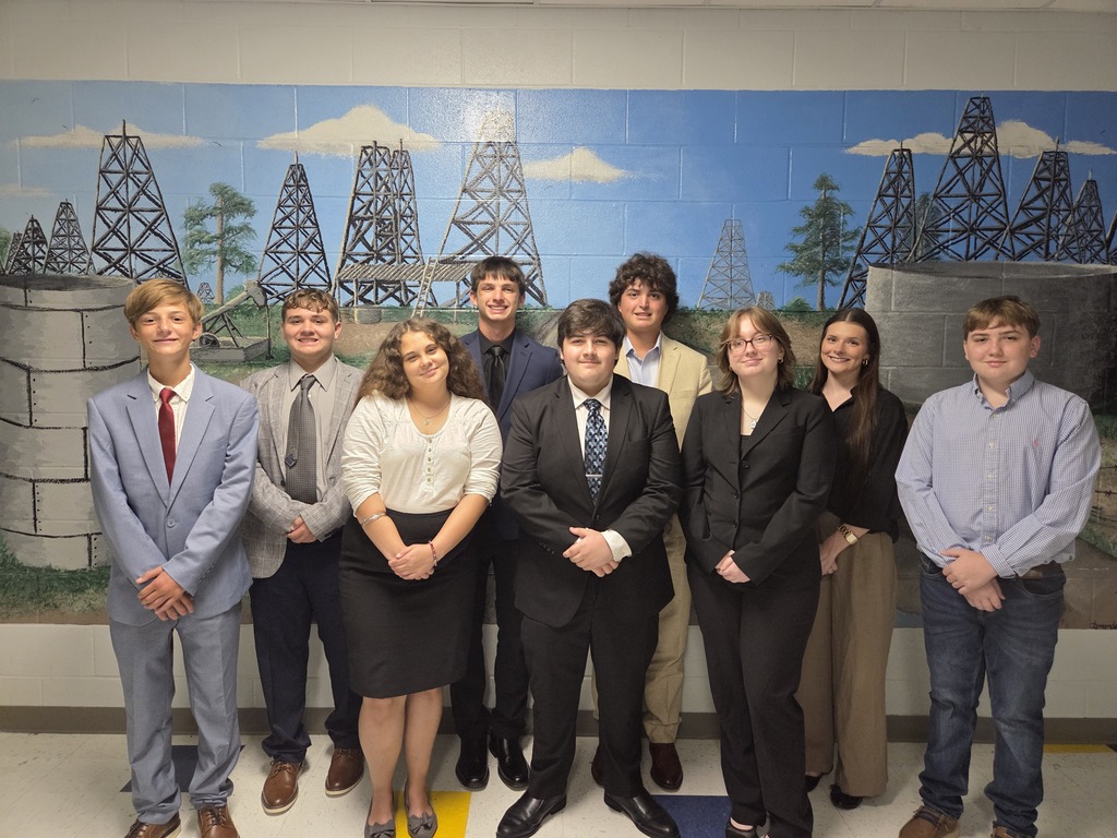 Group of students in formal attire posing for a picture in front of a mural.