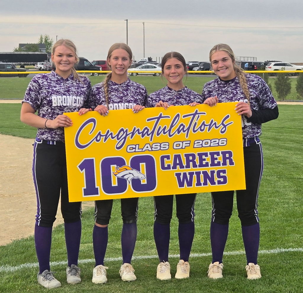 Four softball players holding a sign that says Congratulations Class of 2026, 100 Career Wins