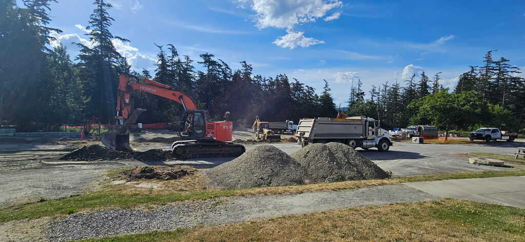 Construction vehicles next to large mounds of gravel