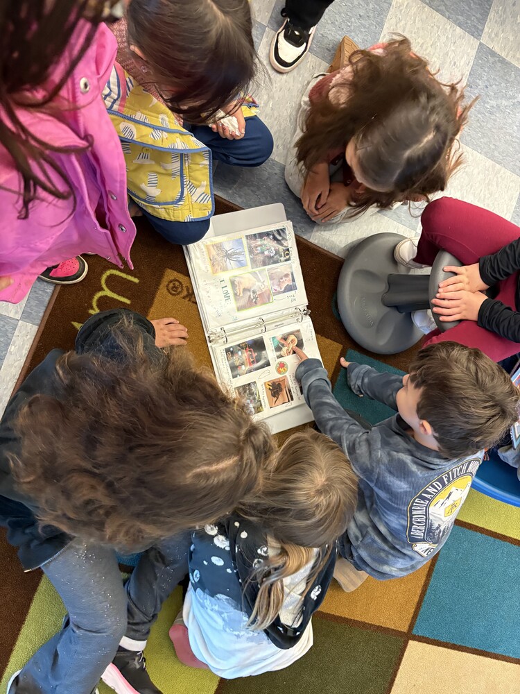 a group of children sitting on the floor circled around an open book.