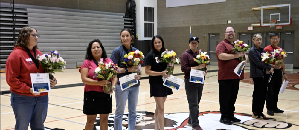 multiple people standing with flowers and award certificates