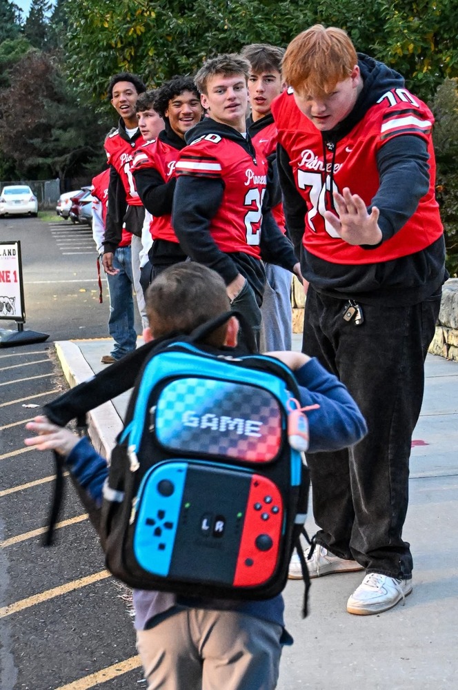 Football players high fiving students