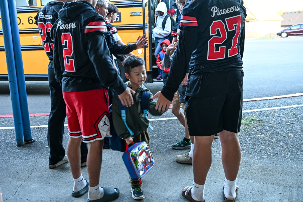 Football players greeting students