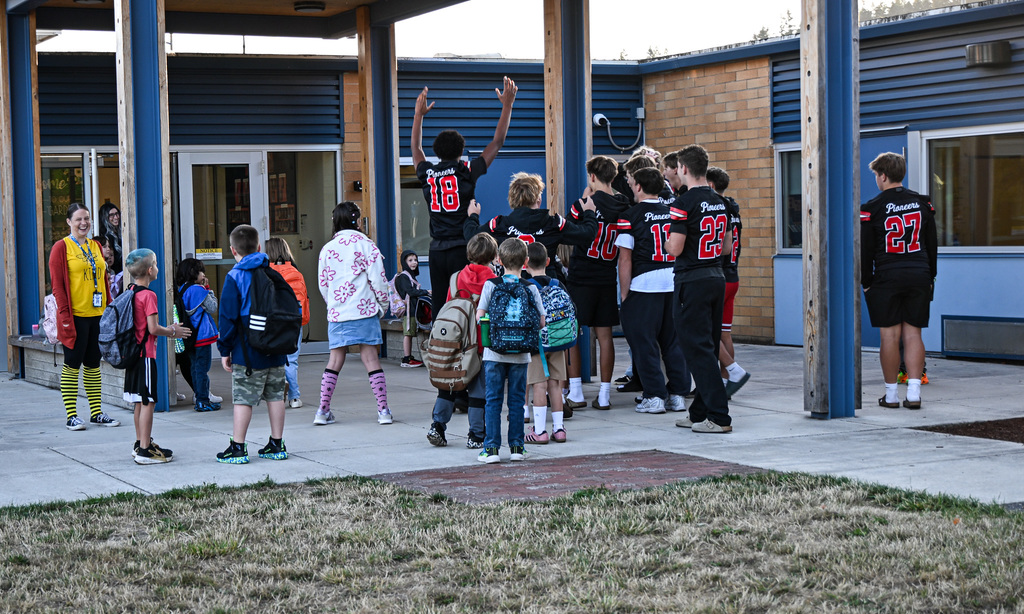 Football players greeting students