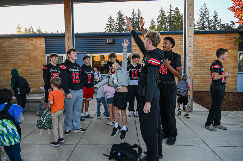 Football players greeting students