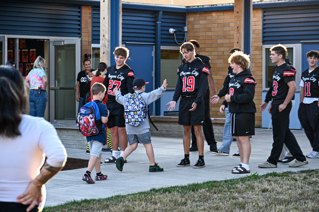 Football players greeting students