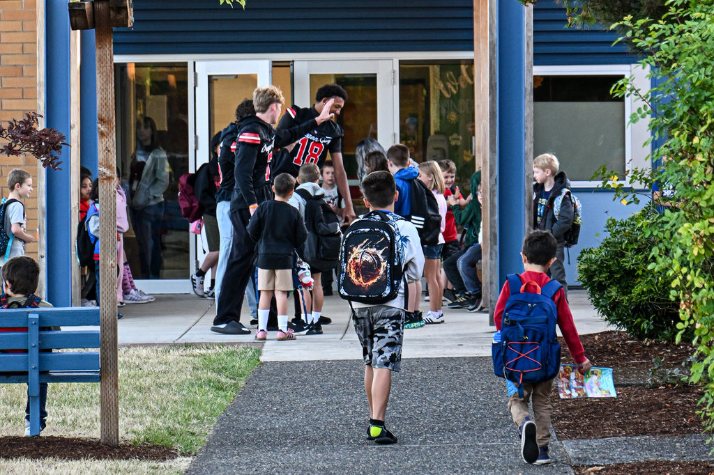 Football players greeting students