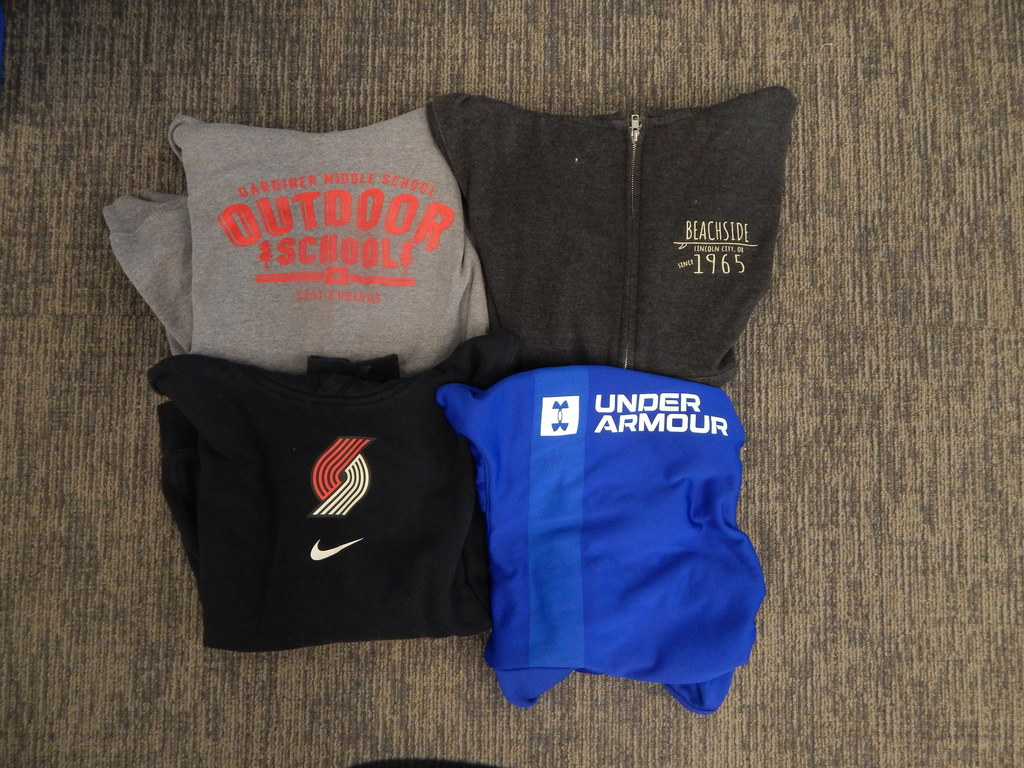 Four sweatshirts - 1 blue under armour, 1 black beachside, 1 grey Outdoor School, 1 black Blazer logo Nike