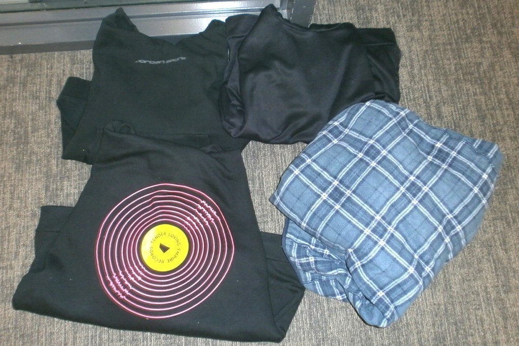 three black sweatshirts, one with pink/yellow "record", one blue check shirt