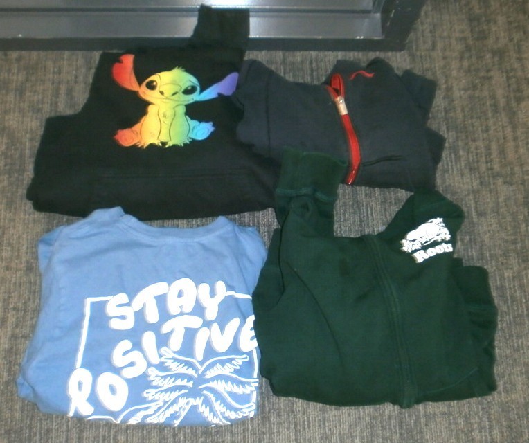 Black stitch sweatshirt, blue stay positive shirt, black Roots shirt, black jacket with red zipper