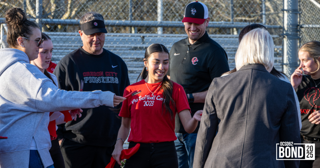 Community members and softball players smiling and standing casually on new turf surface.