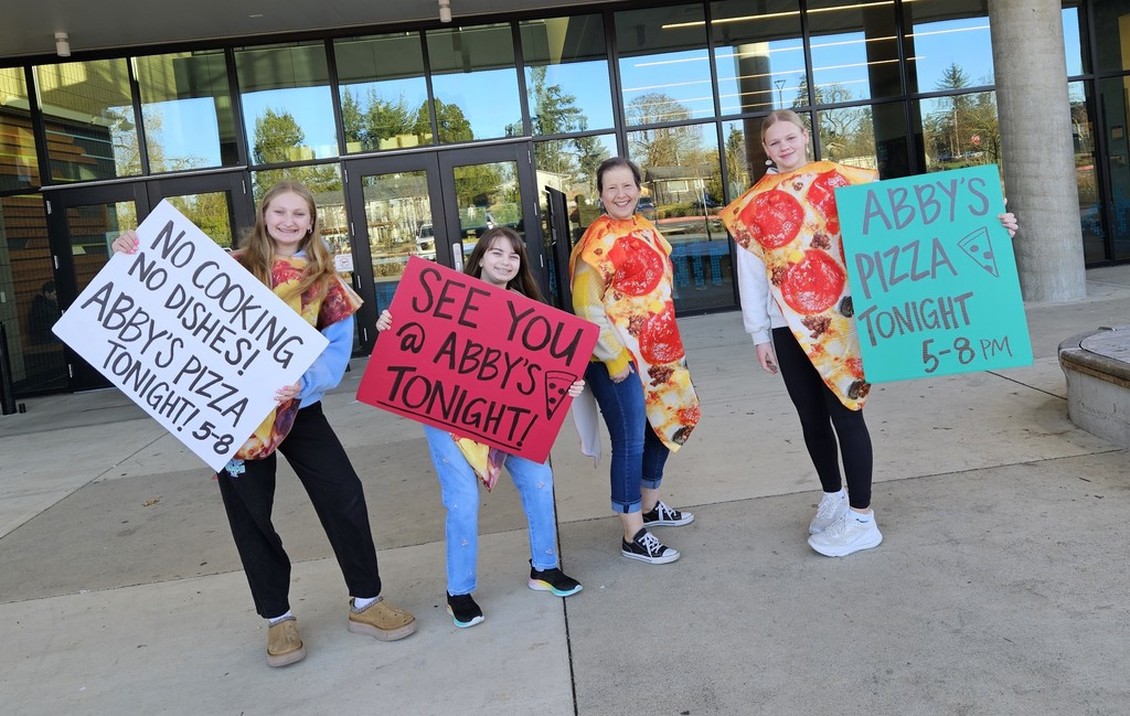 4 people dressed in pizza costumes, holding signs encouraging people to eat at Abby's tonight from 5 - 8 p.m.