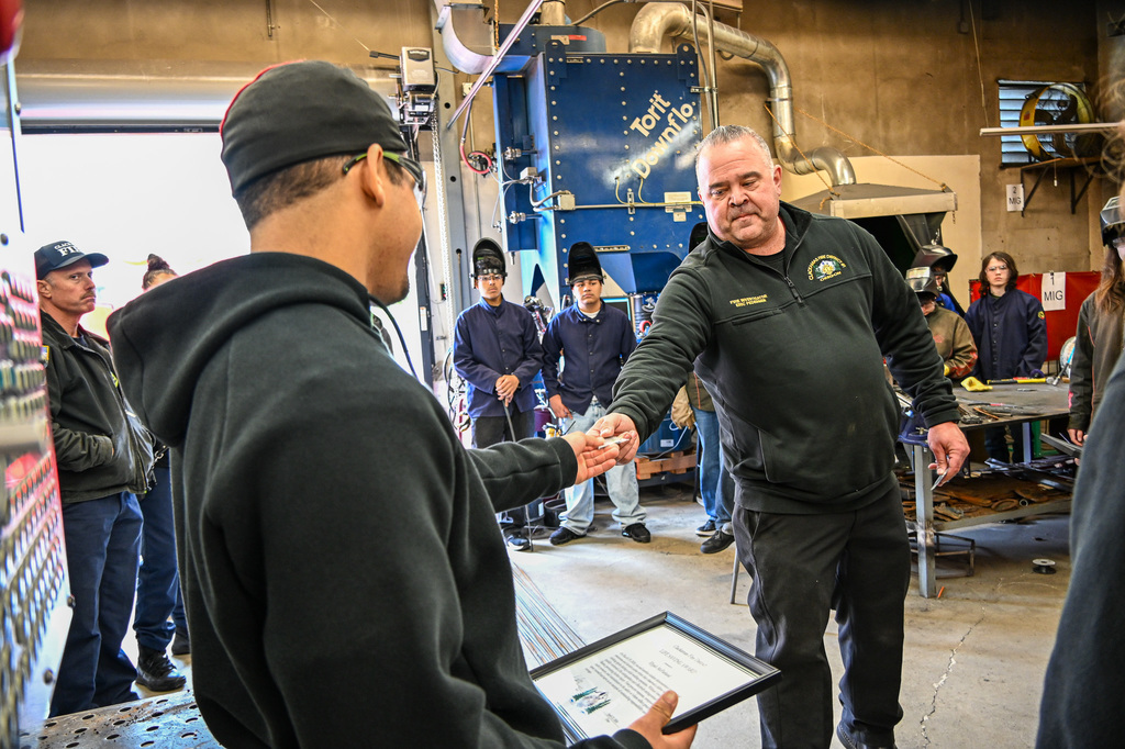 Elyjah being handed the challenge coin by the fire inspector