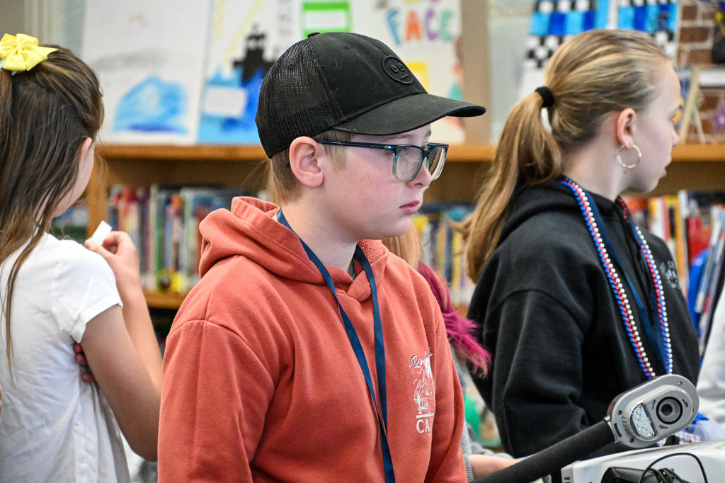 Boy wearing a hat and glasses, listening to instructions