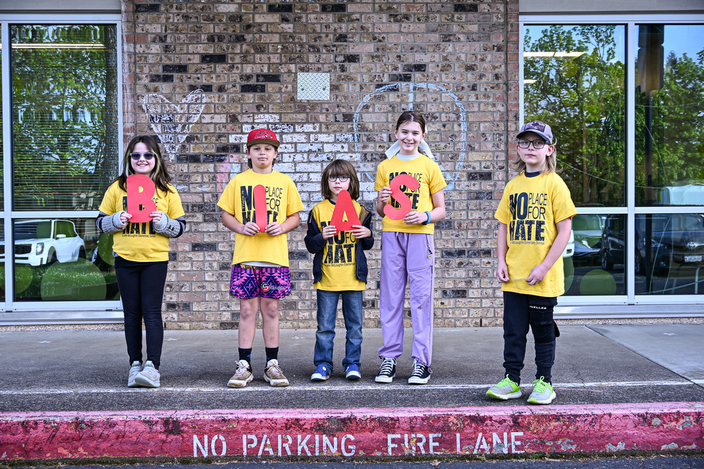 a group of students wearing yellow shirts that say "No Place for Hate" holding letters that spell "B-I-A-S"