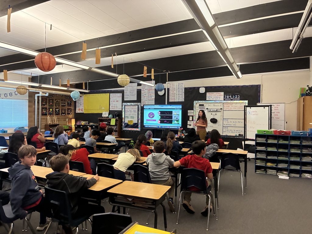 Teacher Carina sharing information about bird and their songs standing in front of a classroom of students