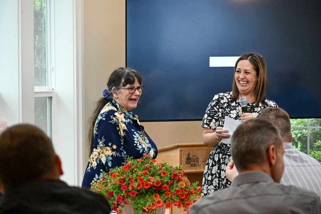 Two women smiling and laughing while standing in front of others