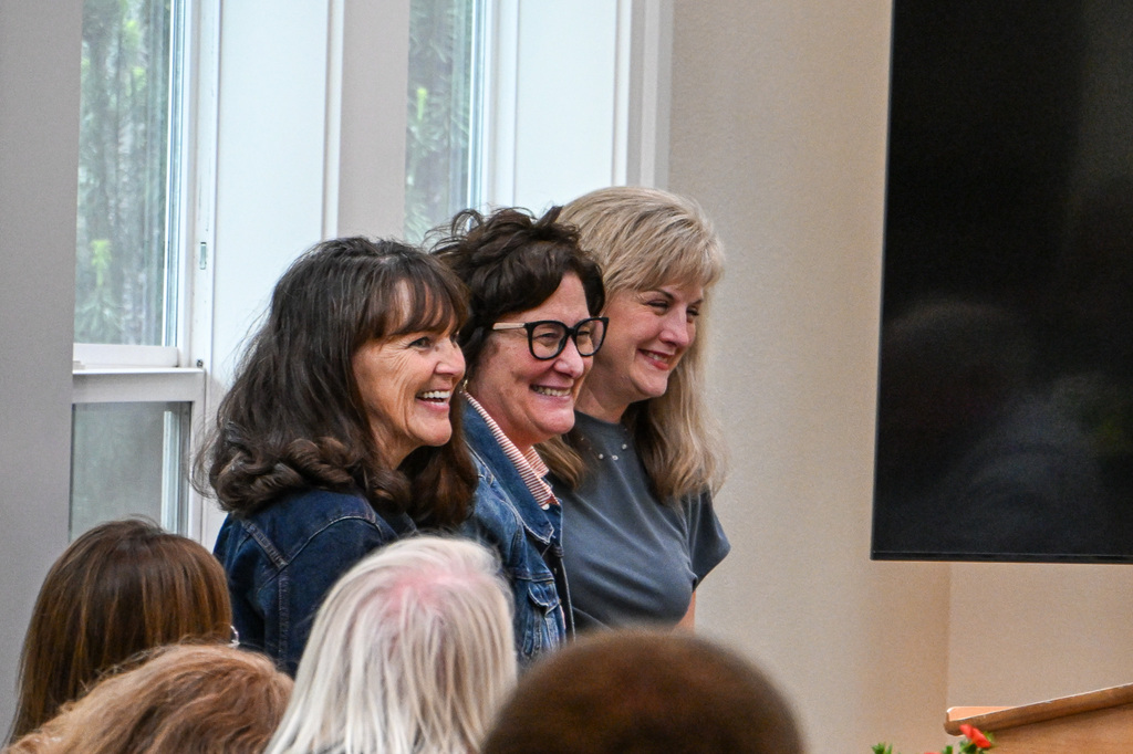 Three women standing in a row smiling