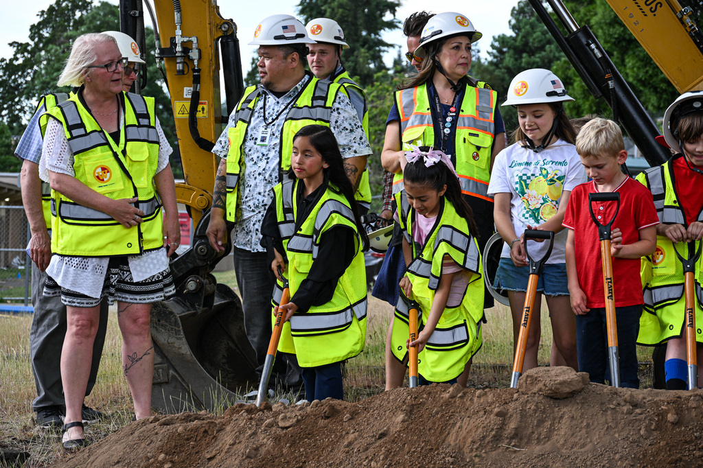 Candy Lane students in yellow safety vests hold ceremonial shovels at a mound of dirt, ready to break ground alongside district staff and bond team members.
