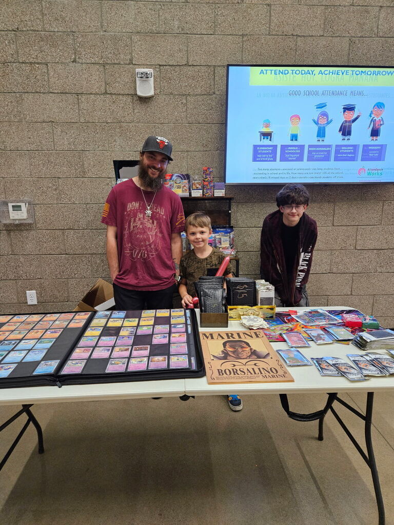 Photo of 3 guys standing behind a table with gaming cards.