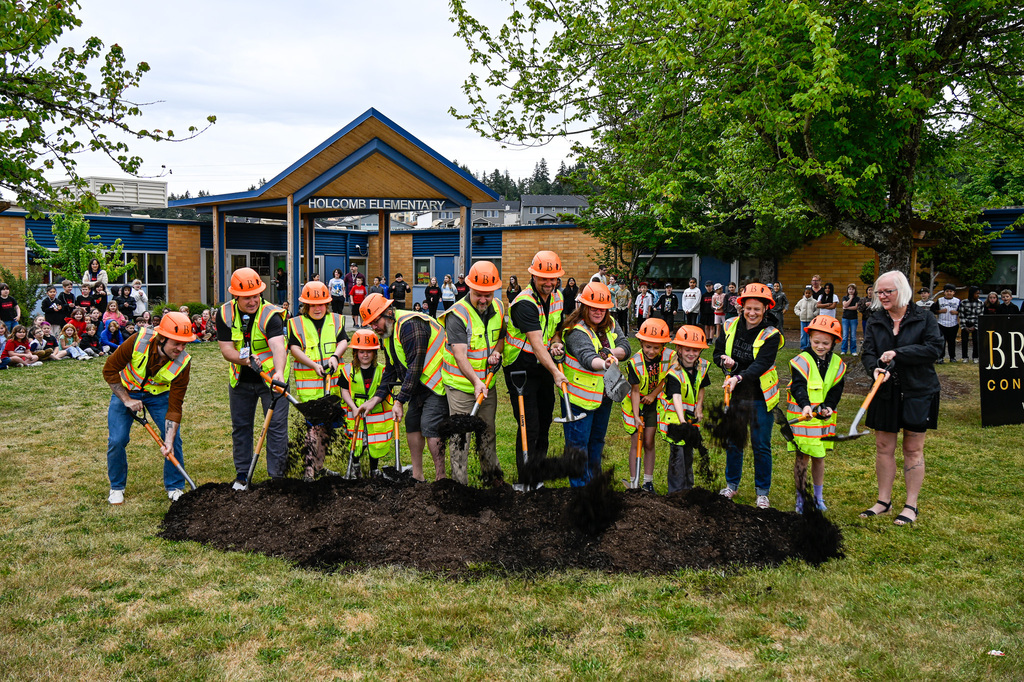 Group with shovels standing behind a dirt pile poised to dig