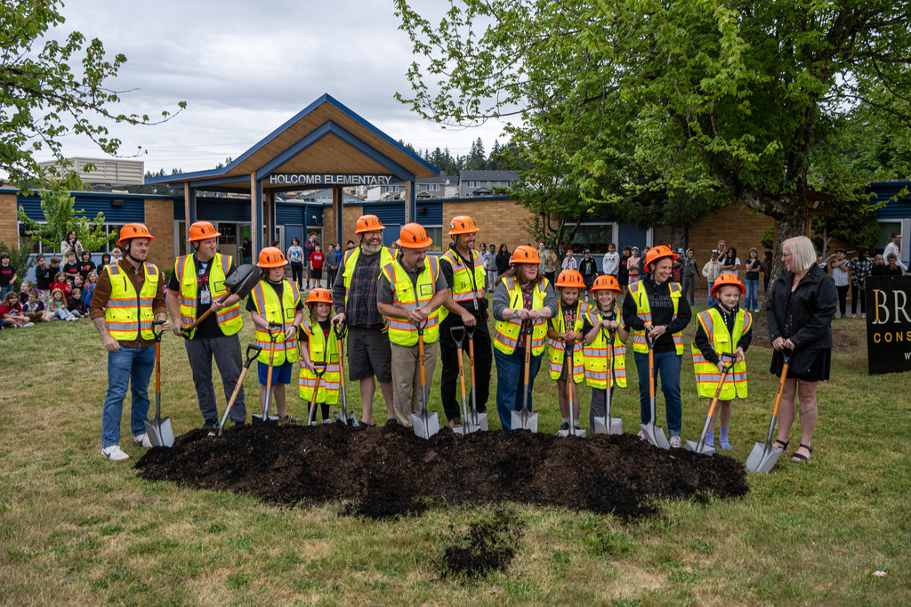 Group with shovels standing behind a dirt pile poised to dig