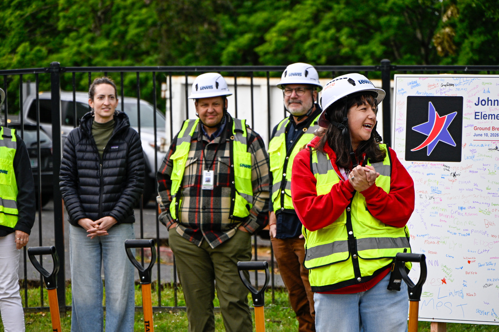 A woman smiling and talking standing in front of a group of other adults