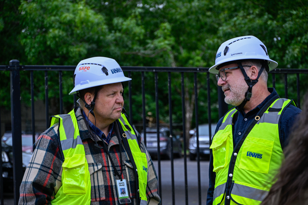 Two men talking wearing hard hats and vests