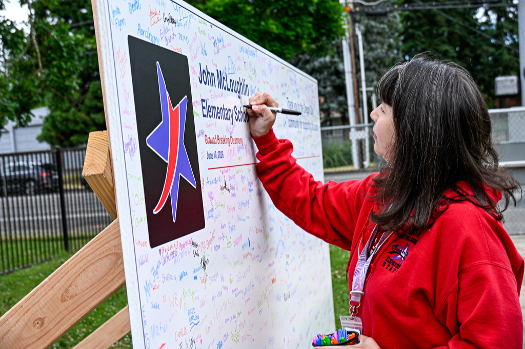 A lady signing a board that says John McLoughlin Elementary