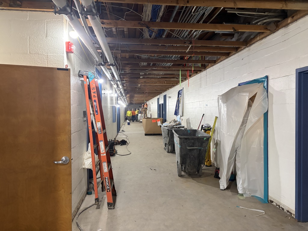 Hallway under construction with ladder. Ceiling is exposed to beams.